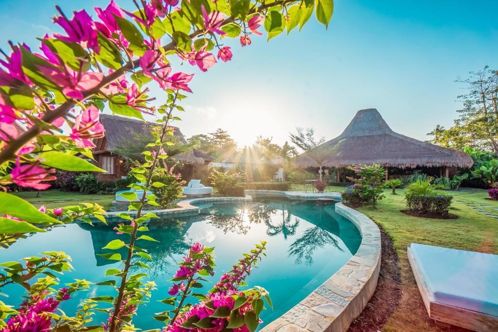 a villa with a swimming pool in a garden with flowers at Green Escape Eco Resort in Uluwatu