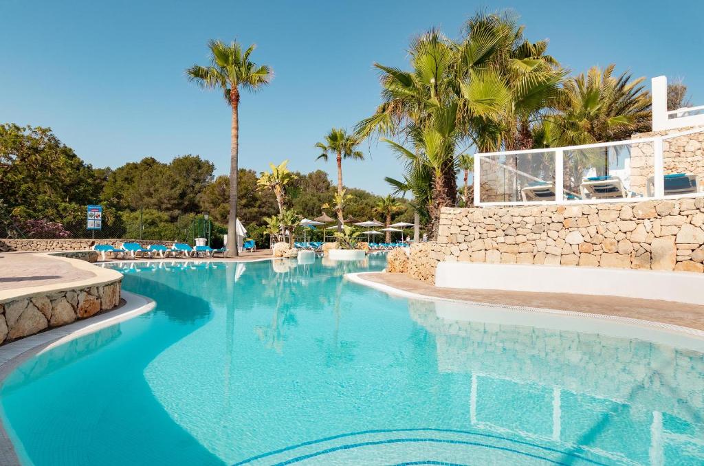 una piscina en un complejo con palmeras en Hotel Palia Puerto del Sol, en Cala d´Or