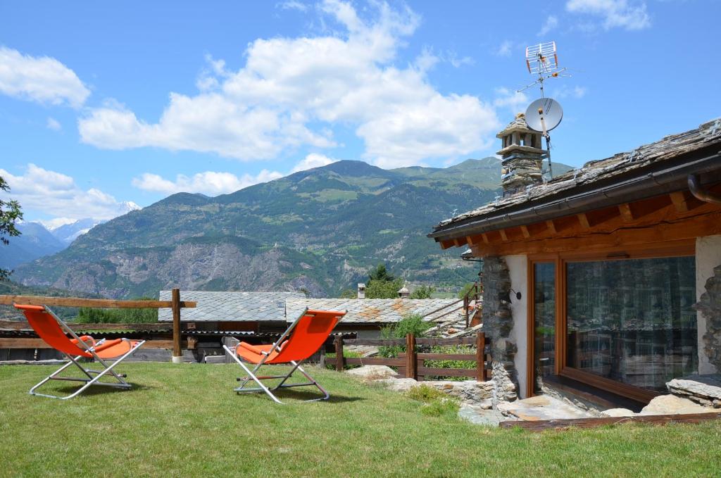 two chairs sitting in the grass next to a house at Holiday house with garden and enchanting view in Villeneuve