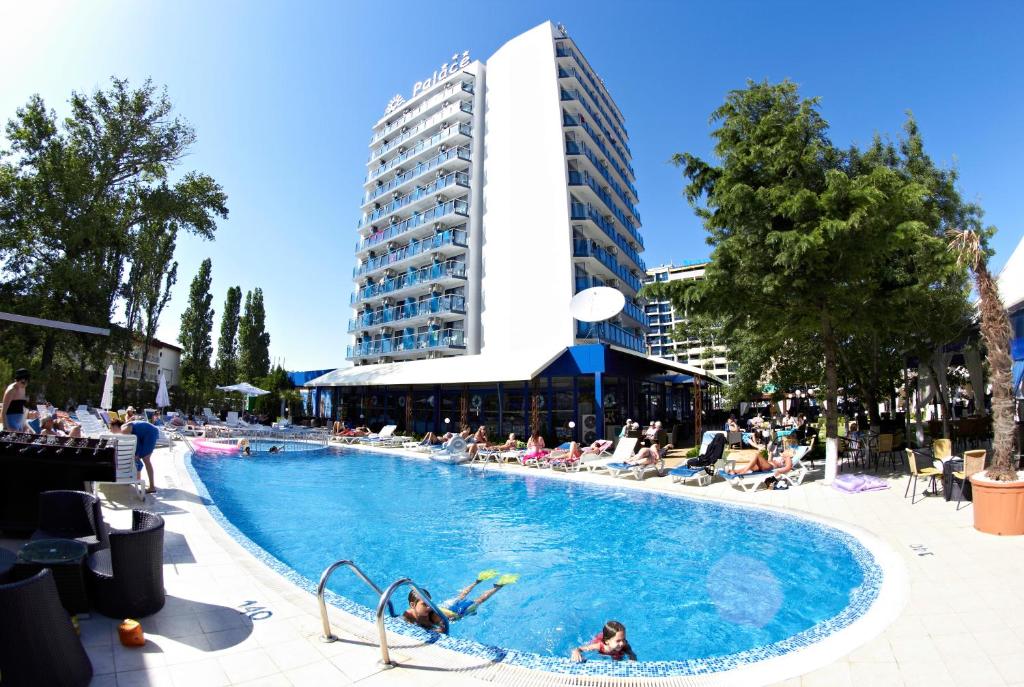 a large swimming pool with people in a building at Palace Hotel in Sunny Beach