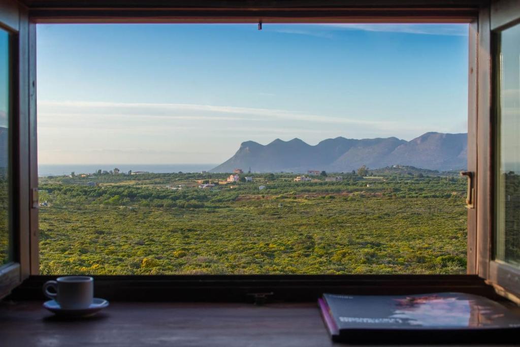 a window with a view of a field and mountains at The Carob Tree Cottage in Kambánion