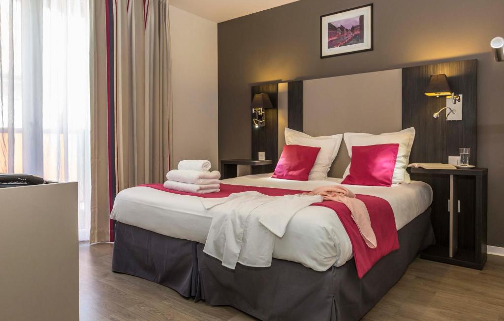 una habitación de hotel con una cama grande con una mujer puesta en ella en Odalys City Colmar La Rose d'Argent en Colmar