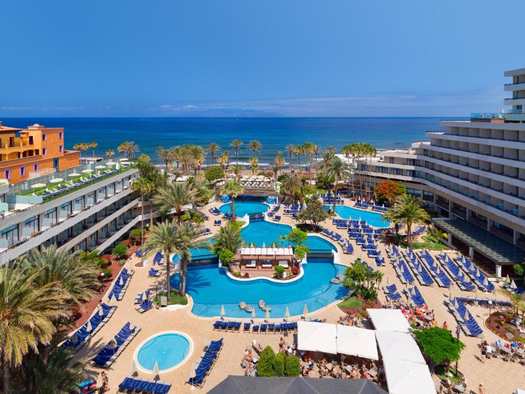 an aerial view of a resort with a pool and the ocean at H10 Conquistador in Playa de las Americas