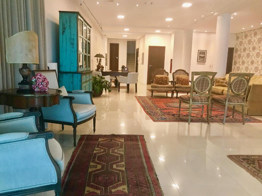 una sala de estar con sillas y mesas y un vestíbulo en Suítes Trindade, en Florianópolis