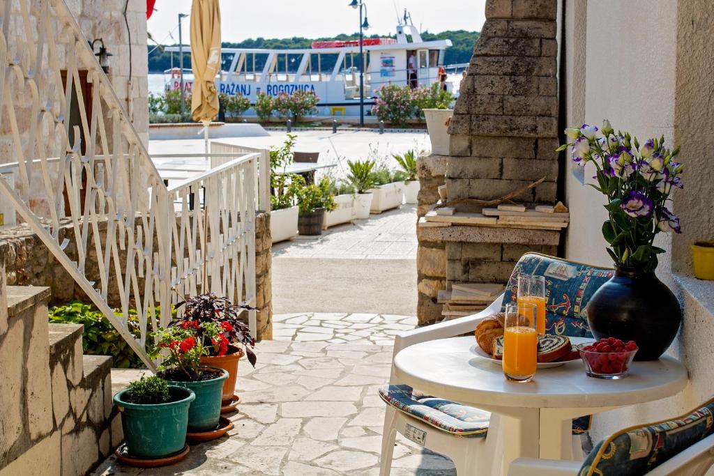 stół z 2 kieliszkami soku pomarańczowego i kwiatami na patio w obiekcie Stone House Grgurevic w Rogoznicy