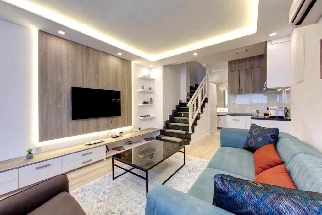 sala de estar con sofá azul y TV en Emerald Apartment, en Mostar