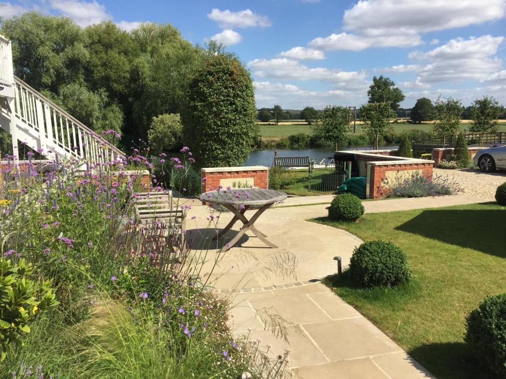 a garden with a bench and a table and flowers at Thames Edge Rooms in Wallingford