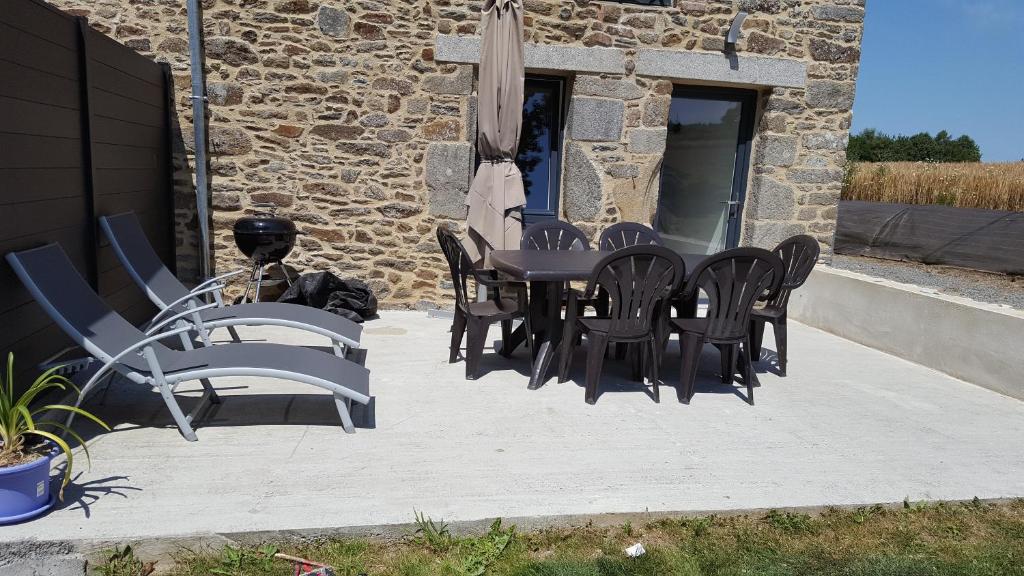 a patio with a table and chairs and an umbrella at So'Home in Saint-Père Marc en Poulet