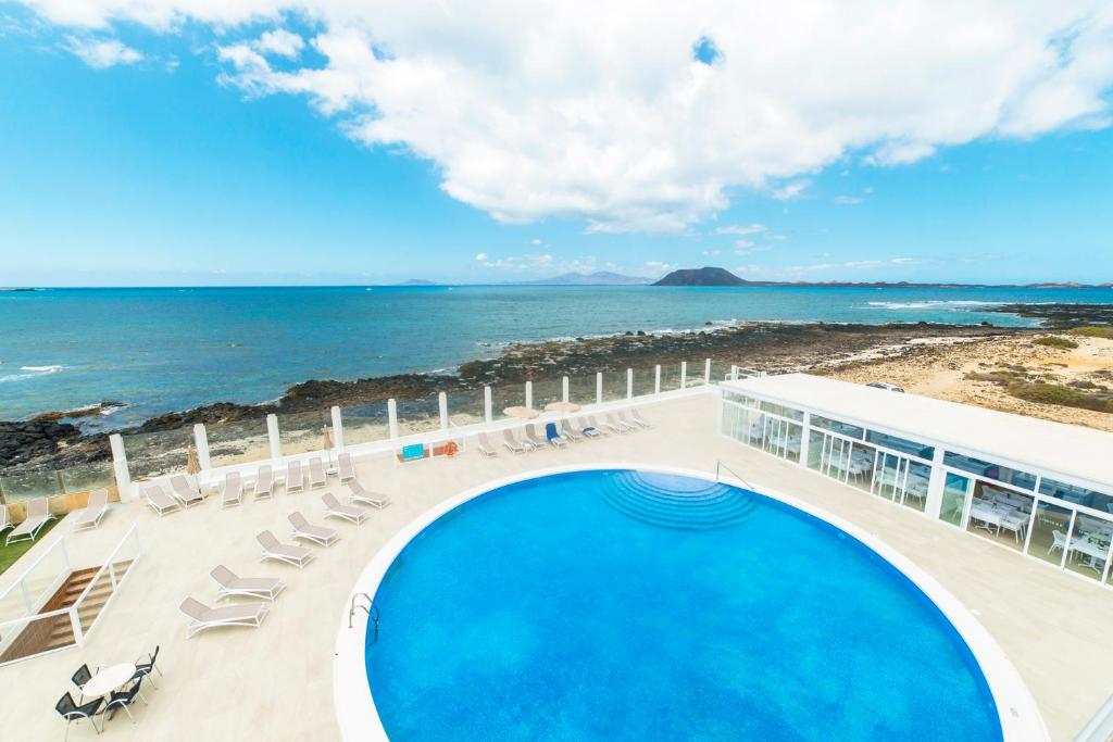 uma vista para uma piscina e para o oceano em Hotel Boutique TAO Caleta Mar em Corralejo