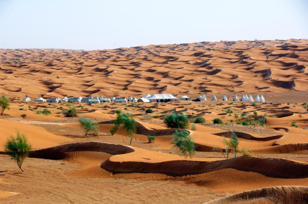 un désert avec des dunes de sable et des maisons au loin dans l'établissement Camp Mars, à Douz