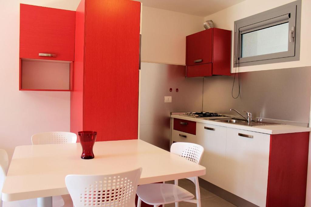 a kitchen with red cabinets and a white table and chairs at Appartamenti Grado in Grado