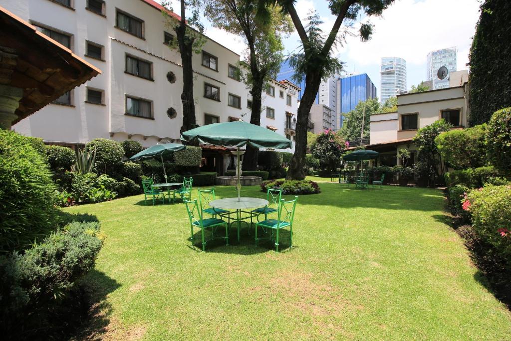 a table and chairs with an umbrella in a yard at Hotel Maria Cristina in Mexico City