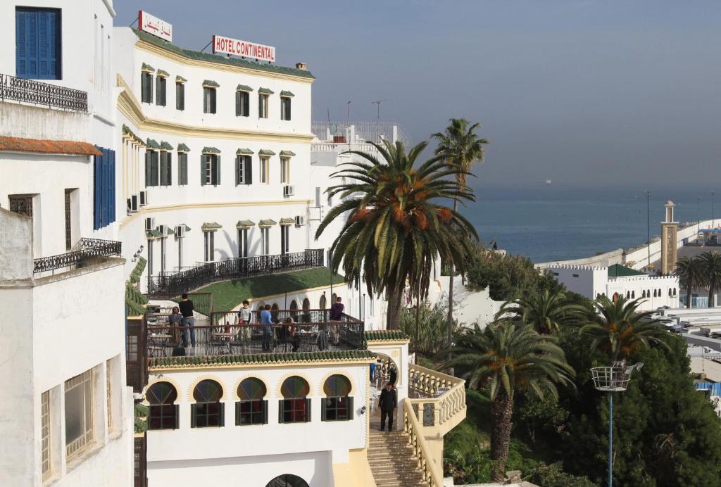 ein weißes Gebäude mit Menschen, die auf einem Balkon stehen in der Unterkunft Hotel Continental in Tangier