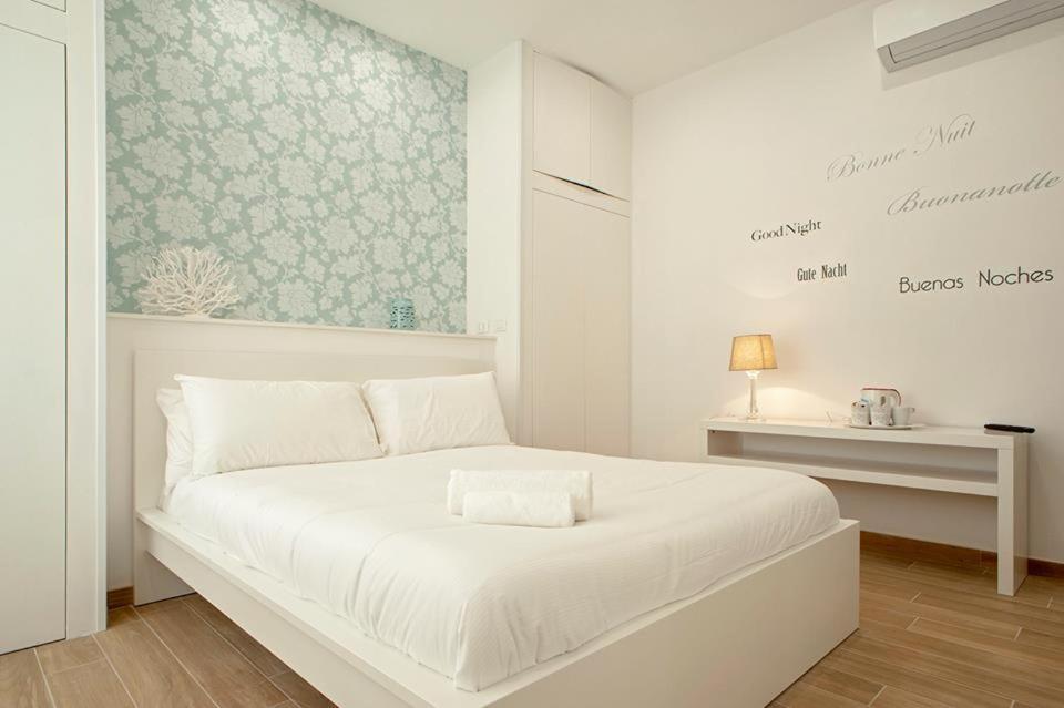 um quarto branco com uma cama branca e uma mesa em My Home-Gorgona em Livorno