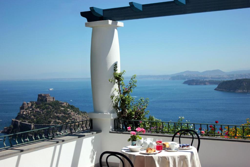 a table on a balcony with a view of the ocean at La Pergola del Torchio in Ischia