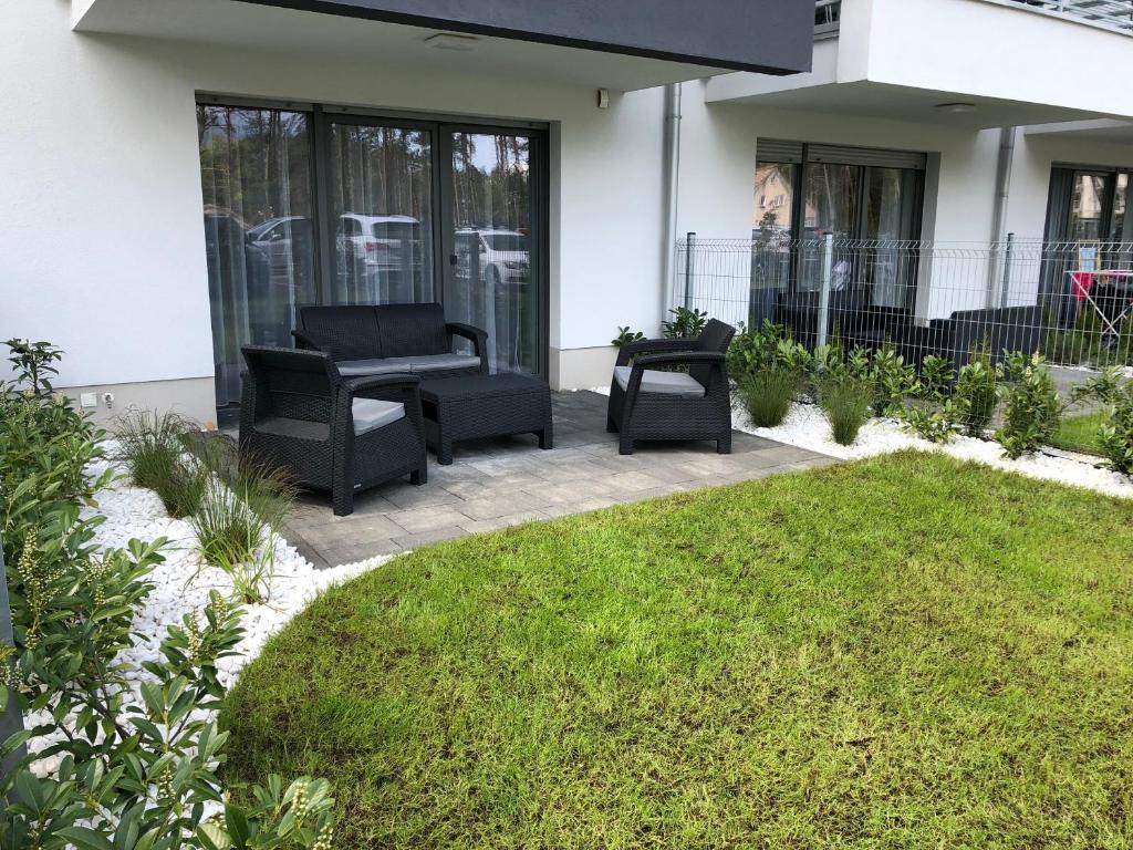 a patio with two chairs and a lawn at Apartament 33BalticBlue in Pogorzelica