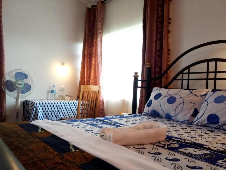 sypialnia z łóżkiem z poduszką i oknem w obiekcie KILIMANJARO MAD MONKEY'S HOTEL w mieście Moshi