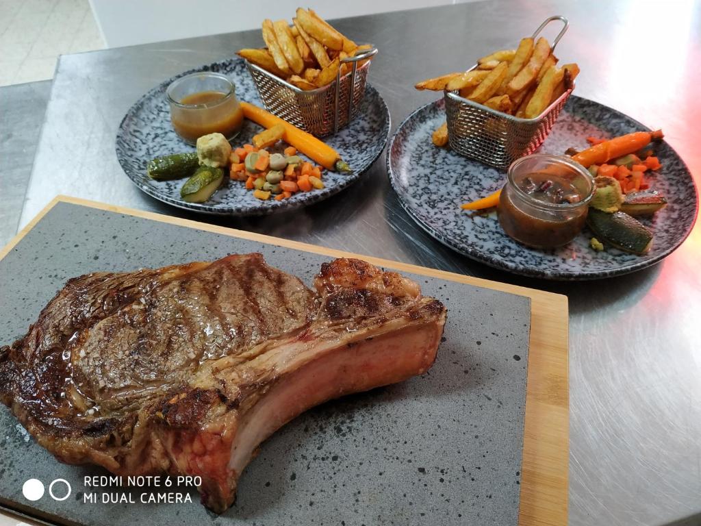 two plates of food with a steak and french fries at Logis Le Saint Hubert in Haybes