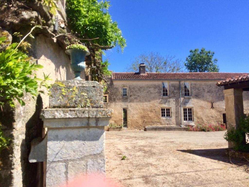 una vecchia casa in pietra con un ampio cortile di Logis de La Touche a Saint-Hilaire-des-Loges