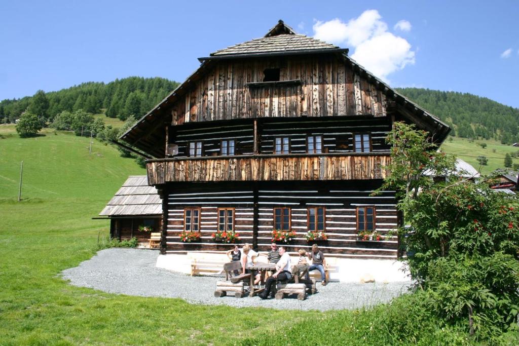 a group of people sitting in front of a cabin at Obervostlhaus - Sehr schöne gemütliche Almhütte der besonderen Art in Ebene Reichenau