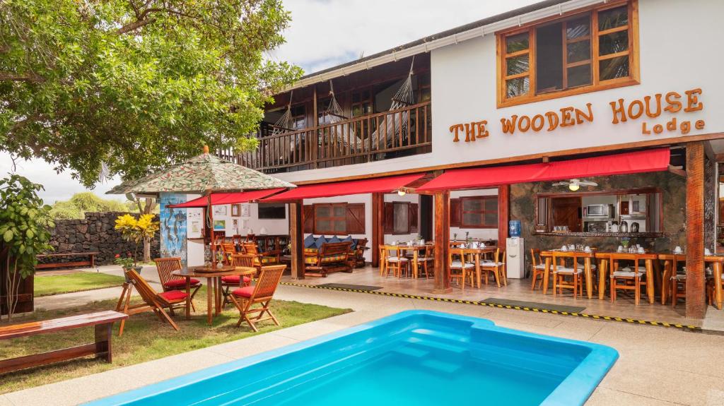 a swimming pool in front of a house with a restaurant at The Wooden House Hotel in Puerto Villamil