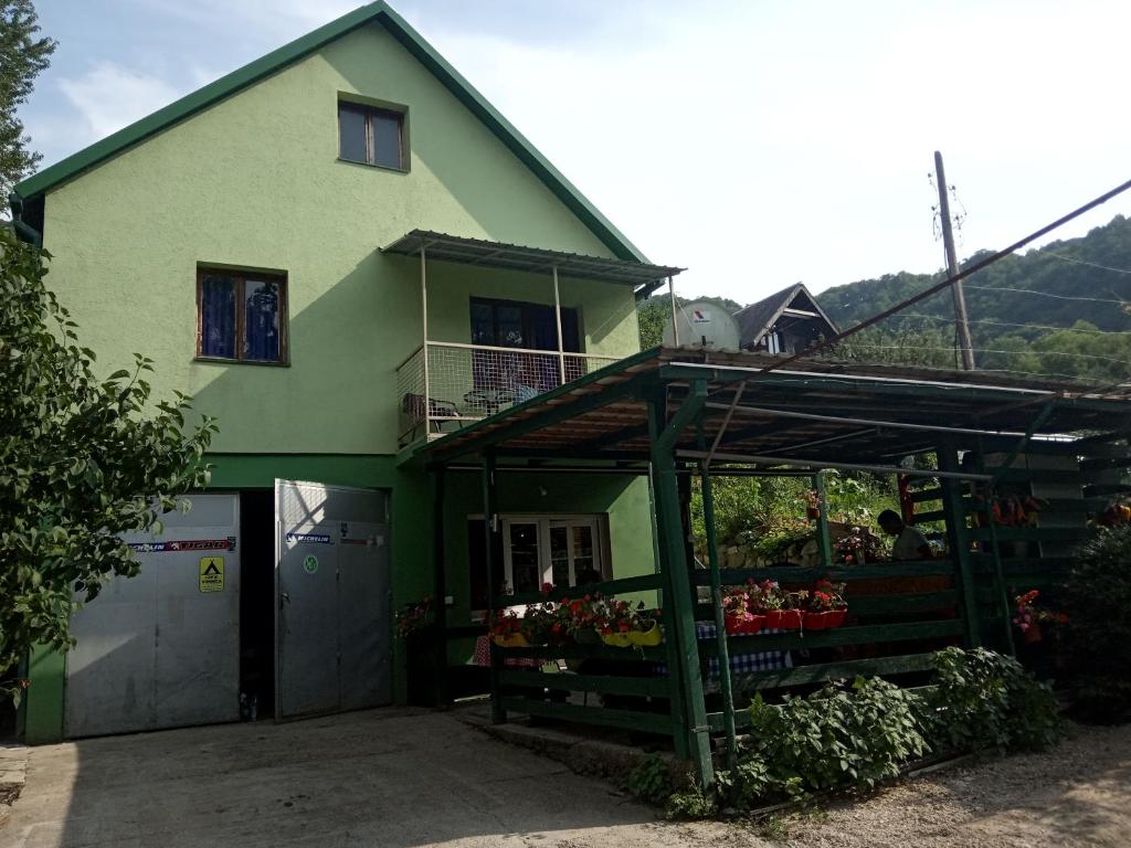 zielony dom z stojakiem warzywnym przed nim w obiekcie Apartmani Lazić w mieście Plužine
