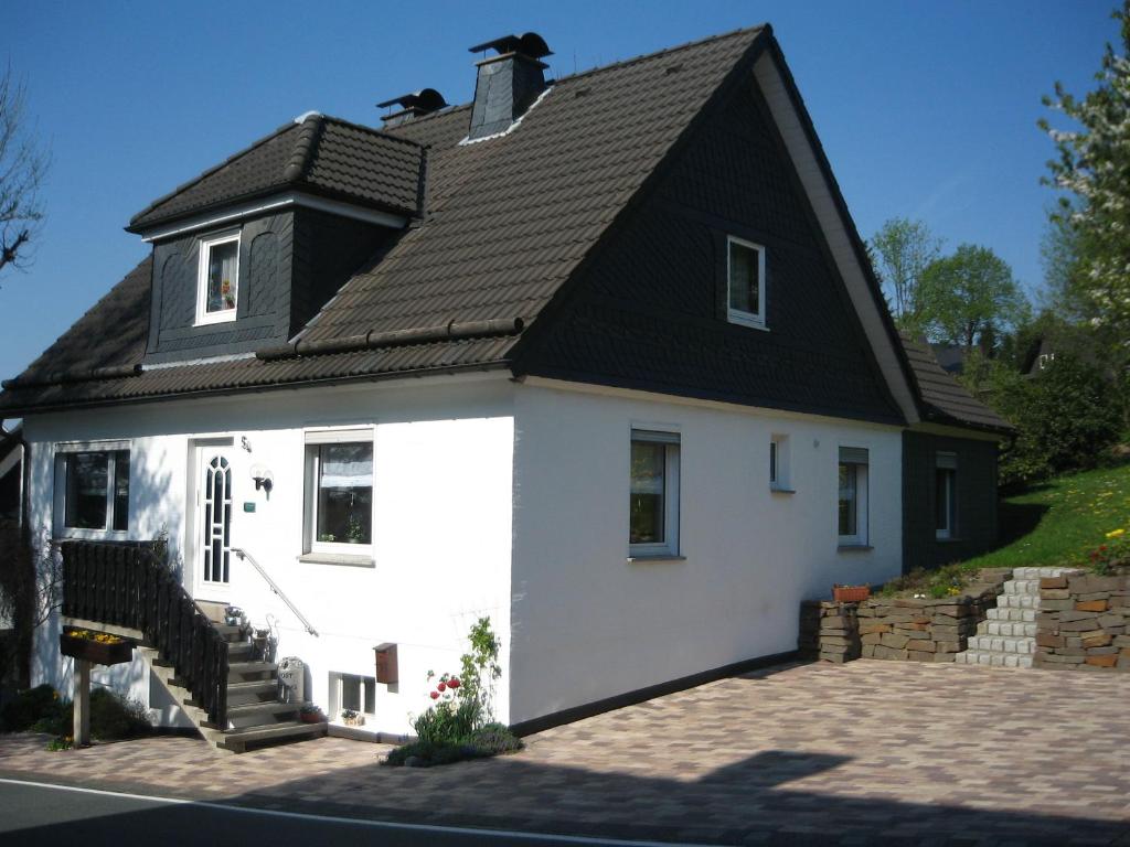 una casa blanca con techo negro en Ferienwohnung Hitzegrad en Winterberg