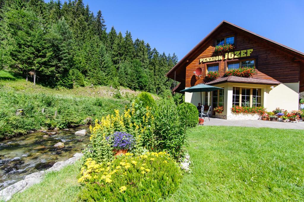 a log cabin with a stream in front of a building at Penzion Jozef in Demanovska Dolina