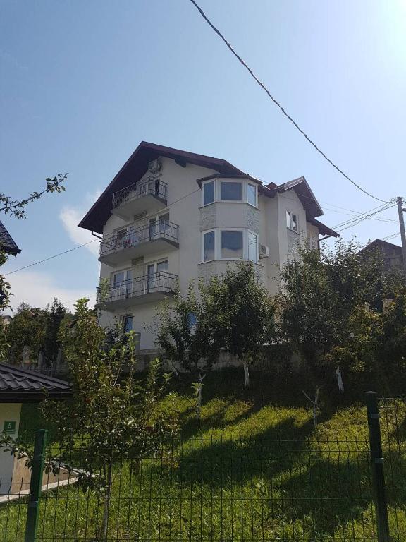 a large white building on a hill behind a fence at Villa Fruit Garden in Sarajevo