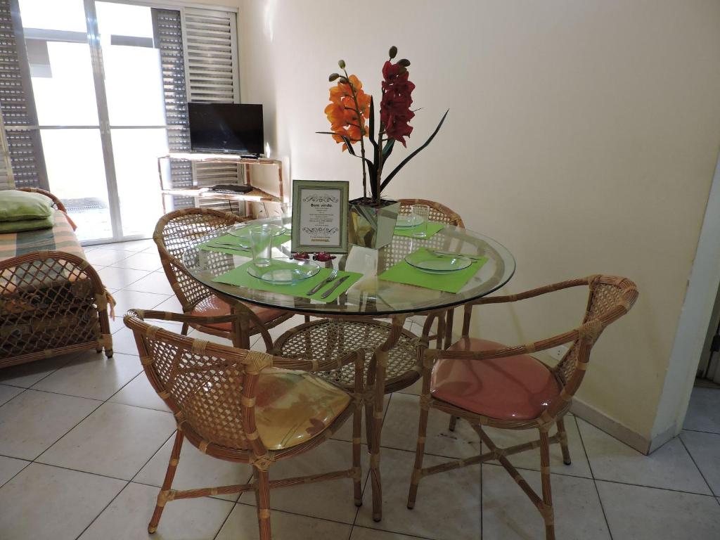 a glass table with chairs and a vase with flowers on it at Condomínio Adriático in Guarujá