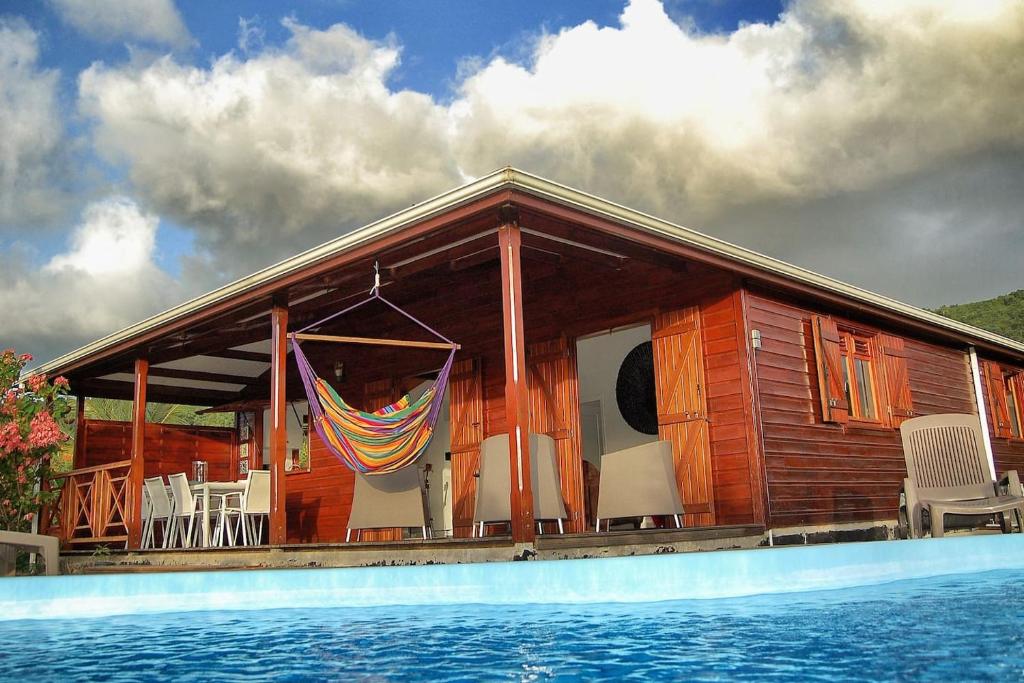 een houten huis met een zwembad ervoor bij Villa Tara Fort Royal in Deshaies