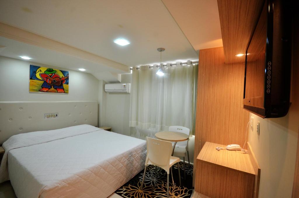um quarto com uma cama, uma mesa e um armário em Hotel Sabino Palace em Mossoró