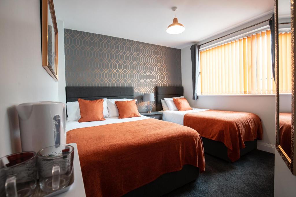 a hotel room with two beds with orange sheets at The Gables Hotel by Cherish Lewis Blackpool in Blackpool