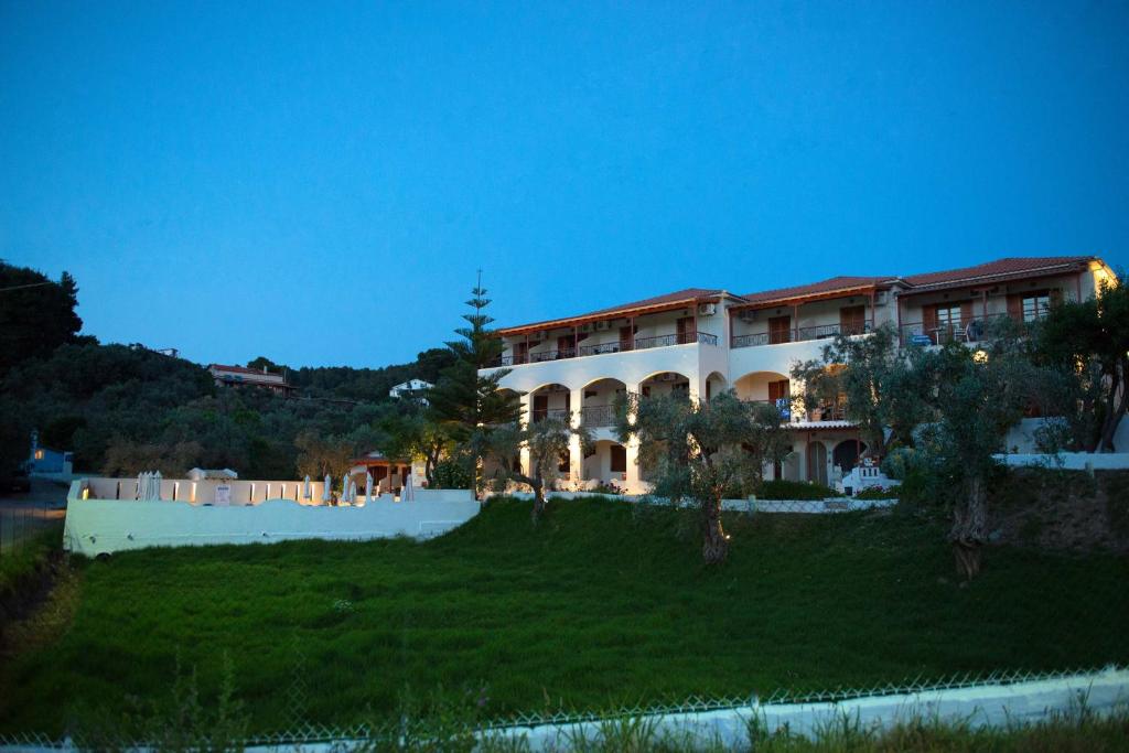 a large building on top of a lush green field at Hotel Marina in Kolios