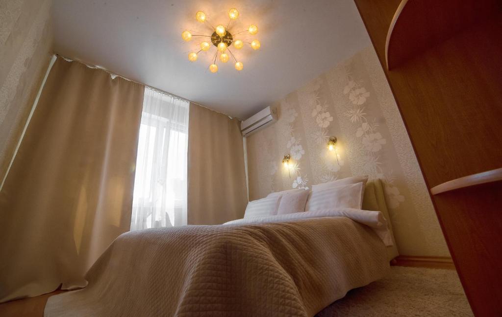 1 dormitorio con 1 cama con lámpara de araña y ventana en PaulMarie Apartments on 40 Stroiteley Street, en Soligorsk