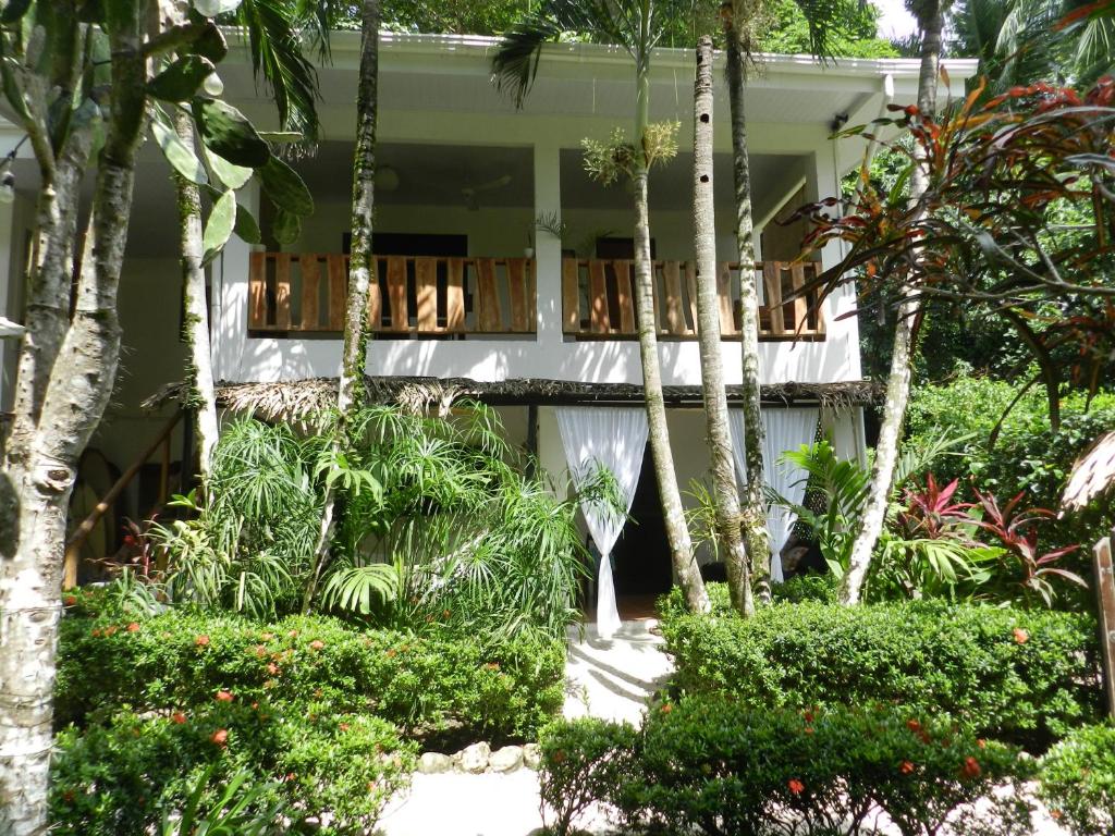 a white house with a balcony and trees at Colibri Apartments - 4 min walk to the Beach! in Santa Teresa Beach