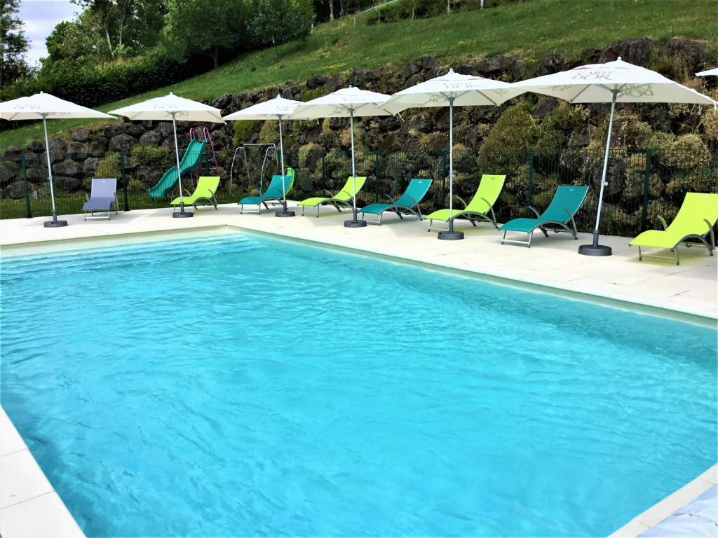 - une piscine avec des chaises longues et des parasols dans l'établissement Hôtel des Barrages, à Brommat