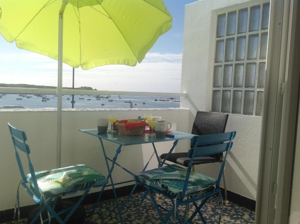 een tafel met 2 stoelen en een parasol op een balkon bij Au Bord Du Chenal in Porspoder