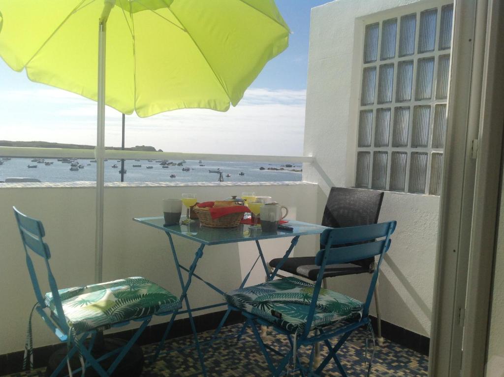 - une table avec deux chaises et un parasol sur le balcon dans l'établissement Au Bord Du Chenal, à Porspoder