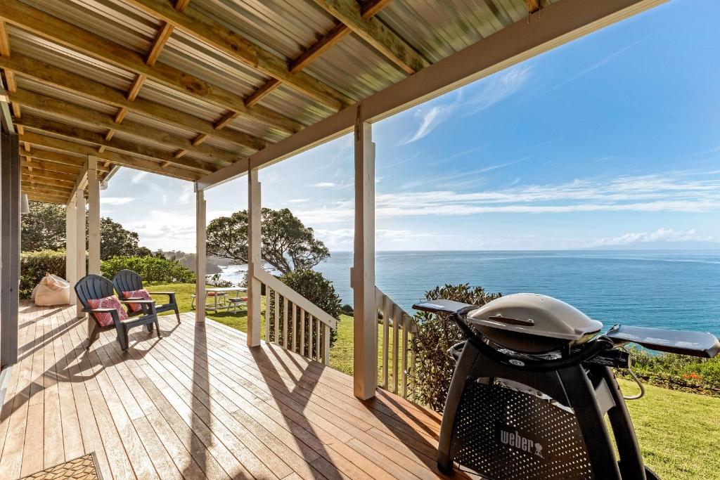 a scooter parked on a deck with a view of the ocean at Moeraki with private walkway to Onetangi Beach by Waiheke Unlimited in Onetangi