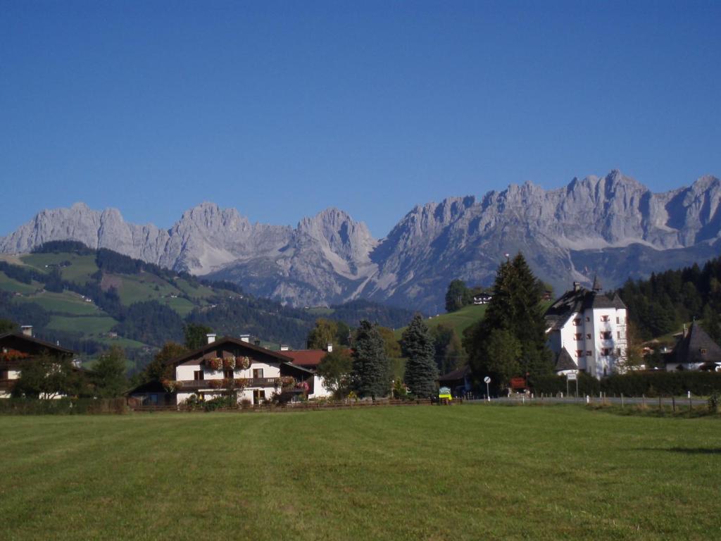 un campo con casas y montañas en el fondo en Ferienwohnungen - Haus Zierl, en Reith bei Kitzbühel
