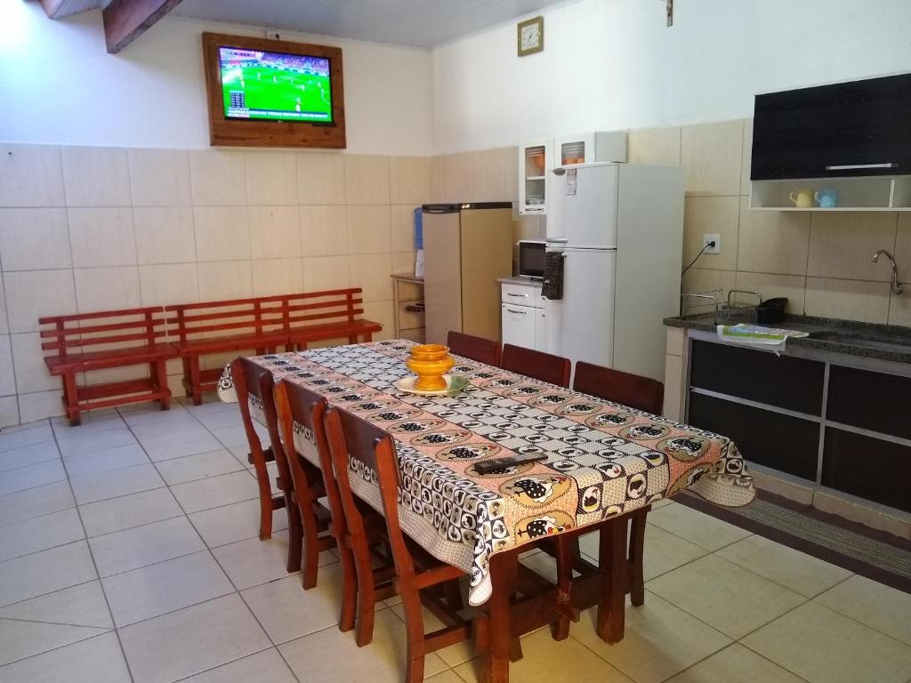 a kitchen with a table with chairs and a television at Casa de Temporada Recanto Fazendinha in Olímpia
