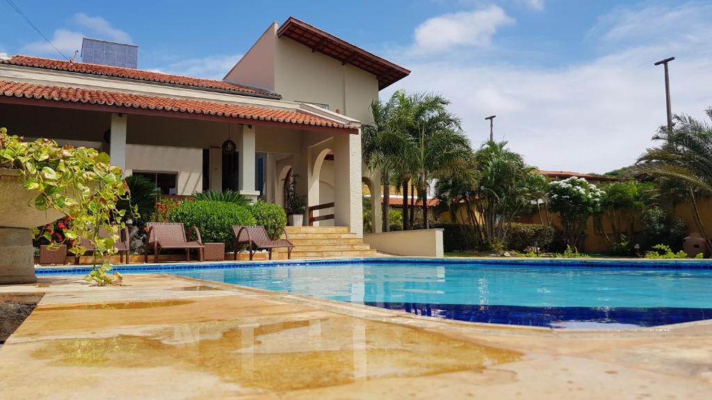 a villa with a swimming pool in front of a house at Pousada Brisa do Mar in Aquiraz