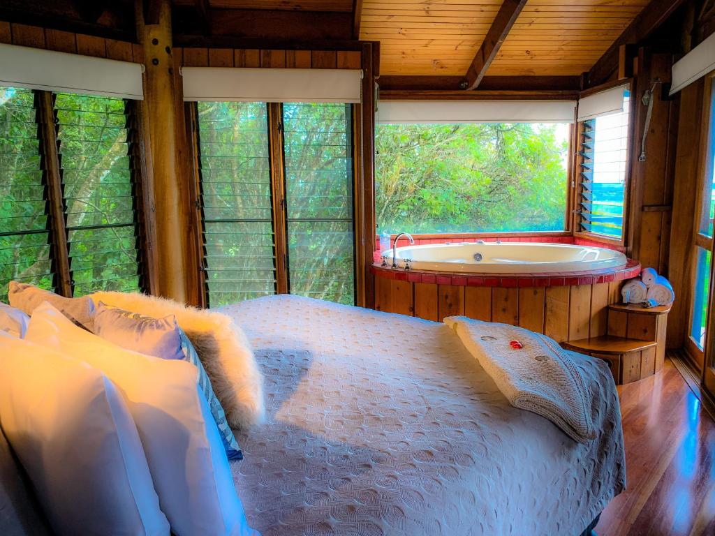 a bedroom with a large bed and a bath tub at Mt Quincan Crater Retreat in Yungaburra