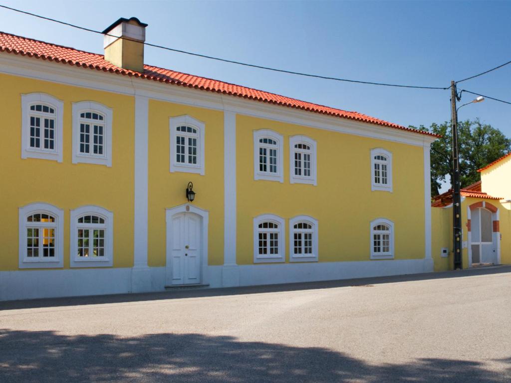 a yellow building with white windows and a red roof at Quinta de Lograssol in Mealhada