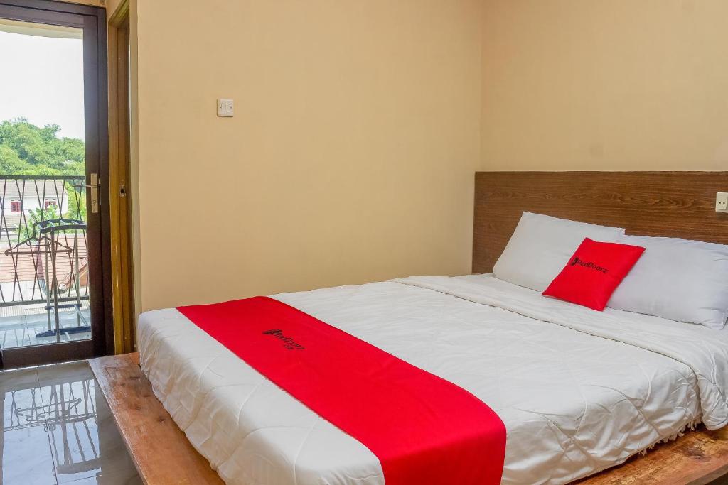 a bedroom with a bed with a red blanket on it at RedDoorz Syariah near Pasar Modern Cikopo in Karawang