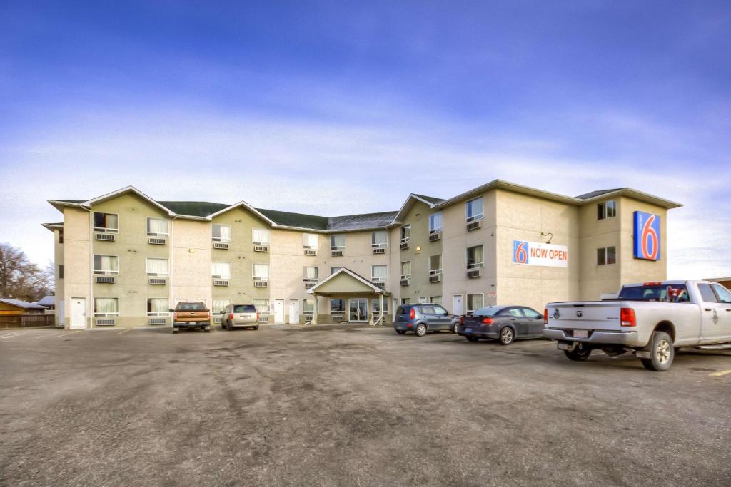 un grand hôtel avec des voitures garées dans un parking dans l'établissement Motel 6-Regina, SK, à Regina