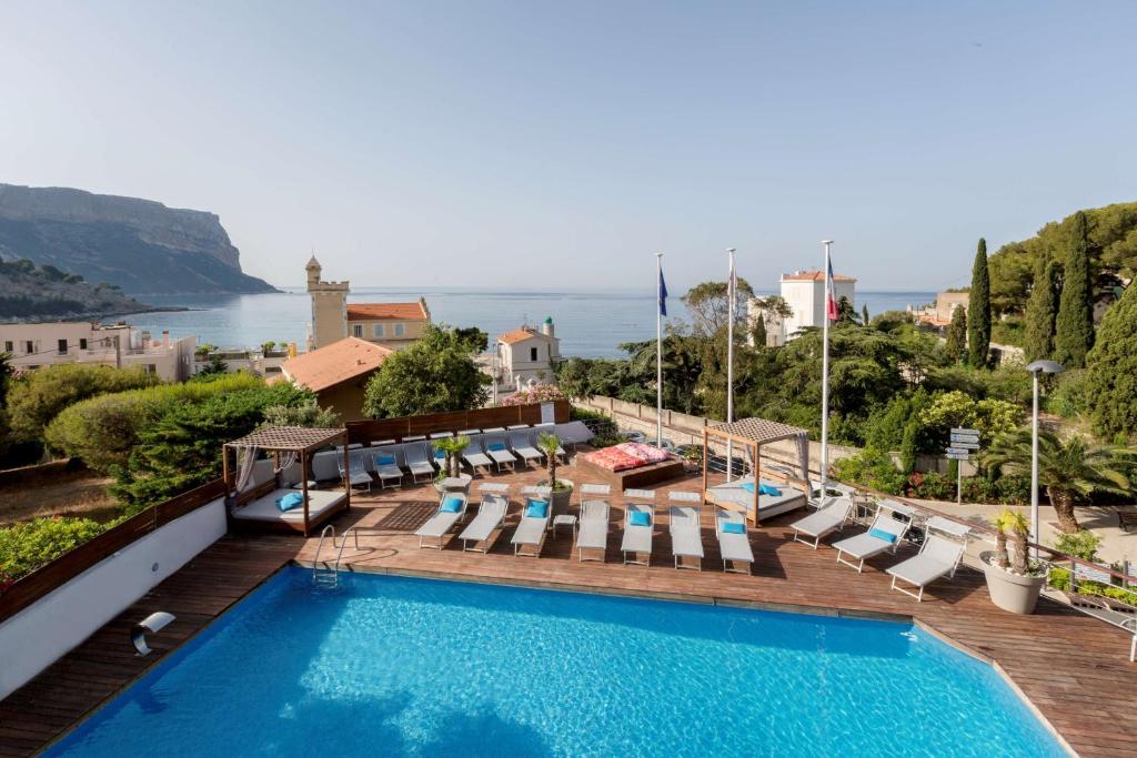 uma piscina do hotel com espreguiçadeiras e o oceano em Best Western Plus Hôtel la Rade em Cassis
