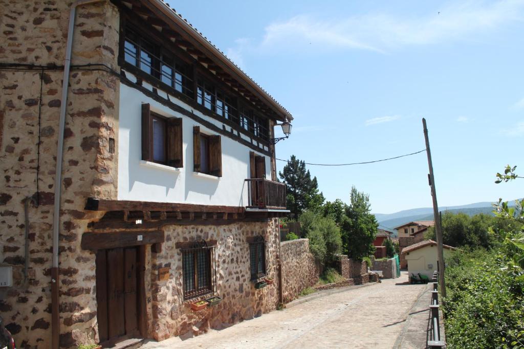 um antigo edifício de pedra com uma varanda numa rua em Casa Rural Marem em El Rasillo