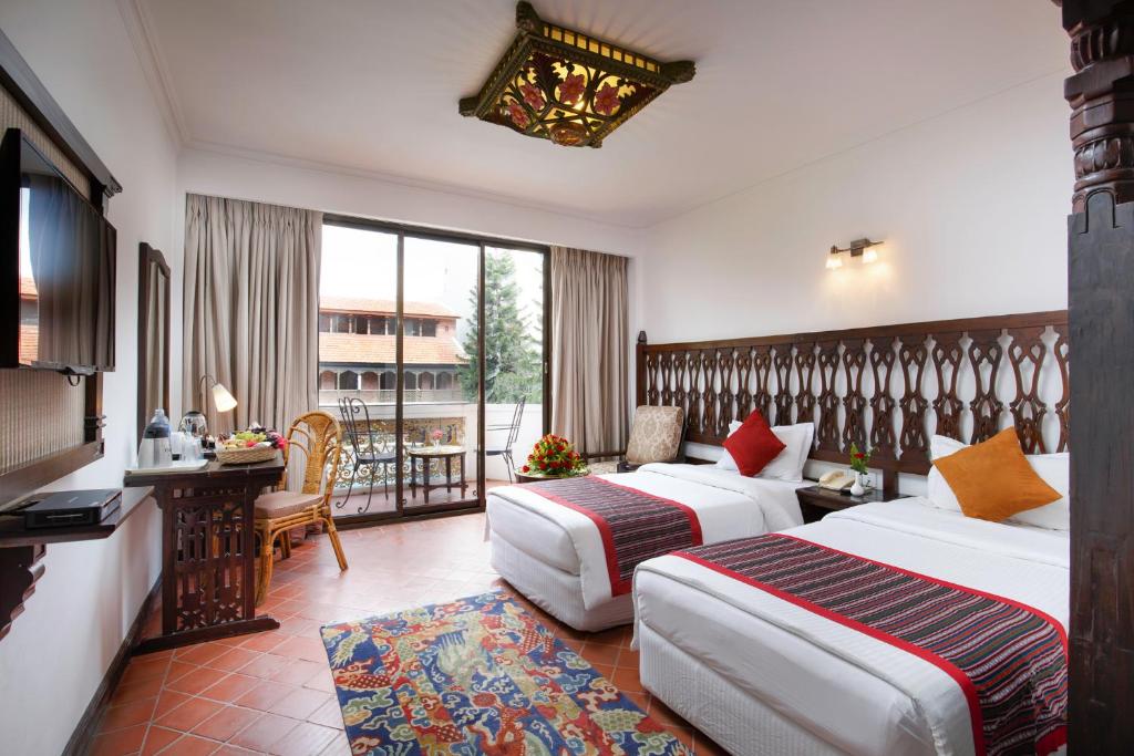 a hotel room with two beds and a balcony at Hotel Manaslu in Kathmandu